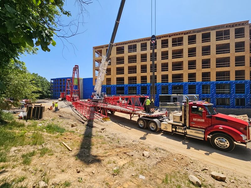 Parking garage construction with a truck, crane, and workers in the foreground.