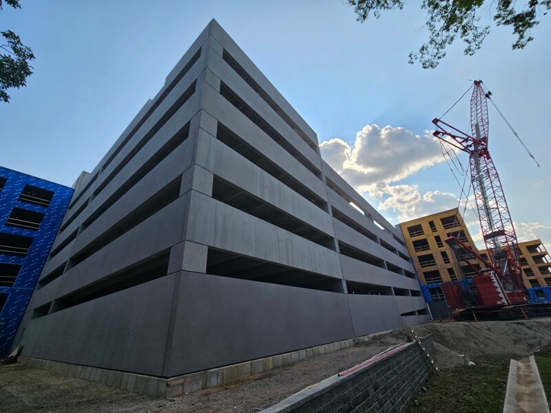 Ground corner view of parking garage. Crane and other buildings in the distance to the right.