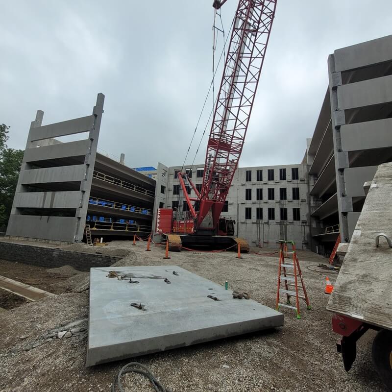 Construction site for a parking garage with a crane as well as a slab lying in the foreground and a slab leaning on something to the right.
