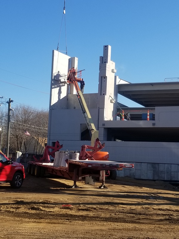Workers using a lift to work on a piece of a structure wall.