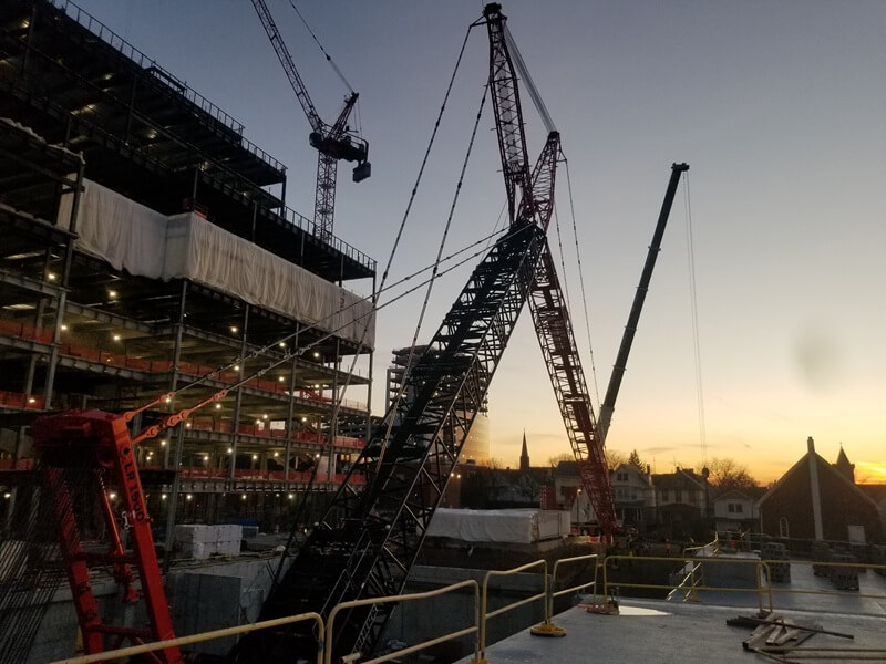Ground view of construction site during sunset. Partially constructed building and a crane in the picture.