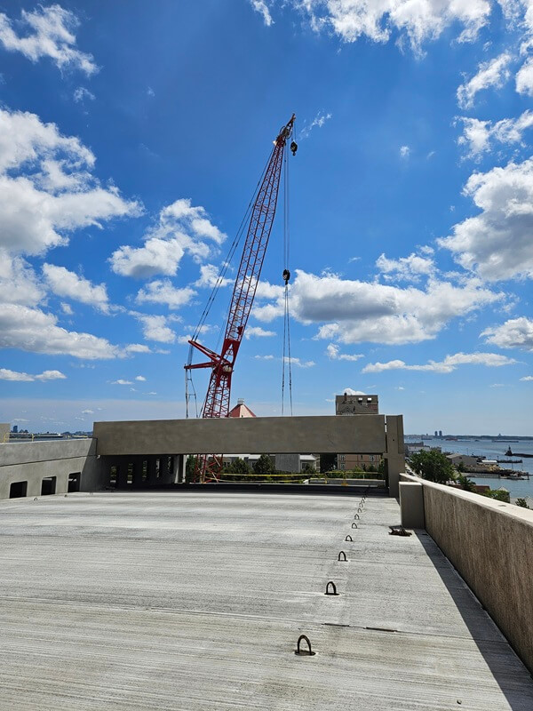 View from the top of the Point Liberte Apartment parking garage. Cloudy blue sky and crane in background.
