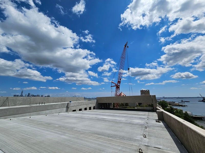 View from the top of the Point Liberte Apartment parking garage. Cloudy blue sky and crane in background.