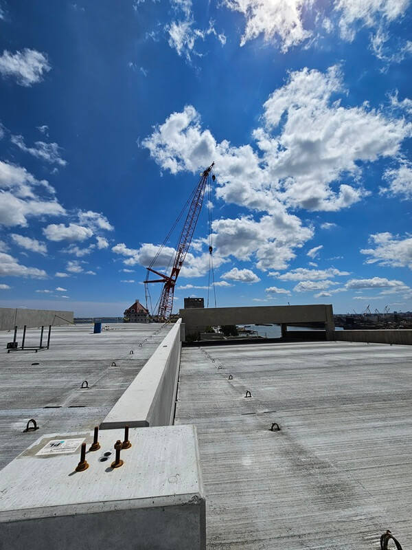 View from the top of the Point Liberte Apartment parking garage. Cloudy blue sky and crane in background.